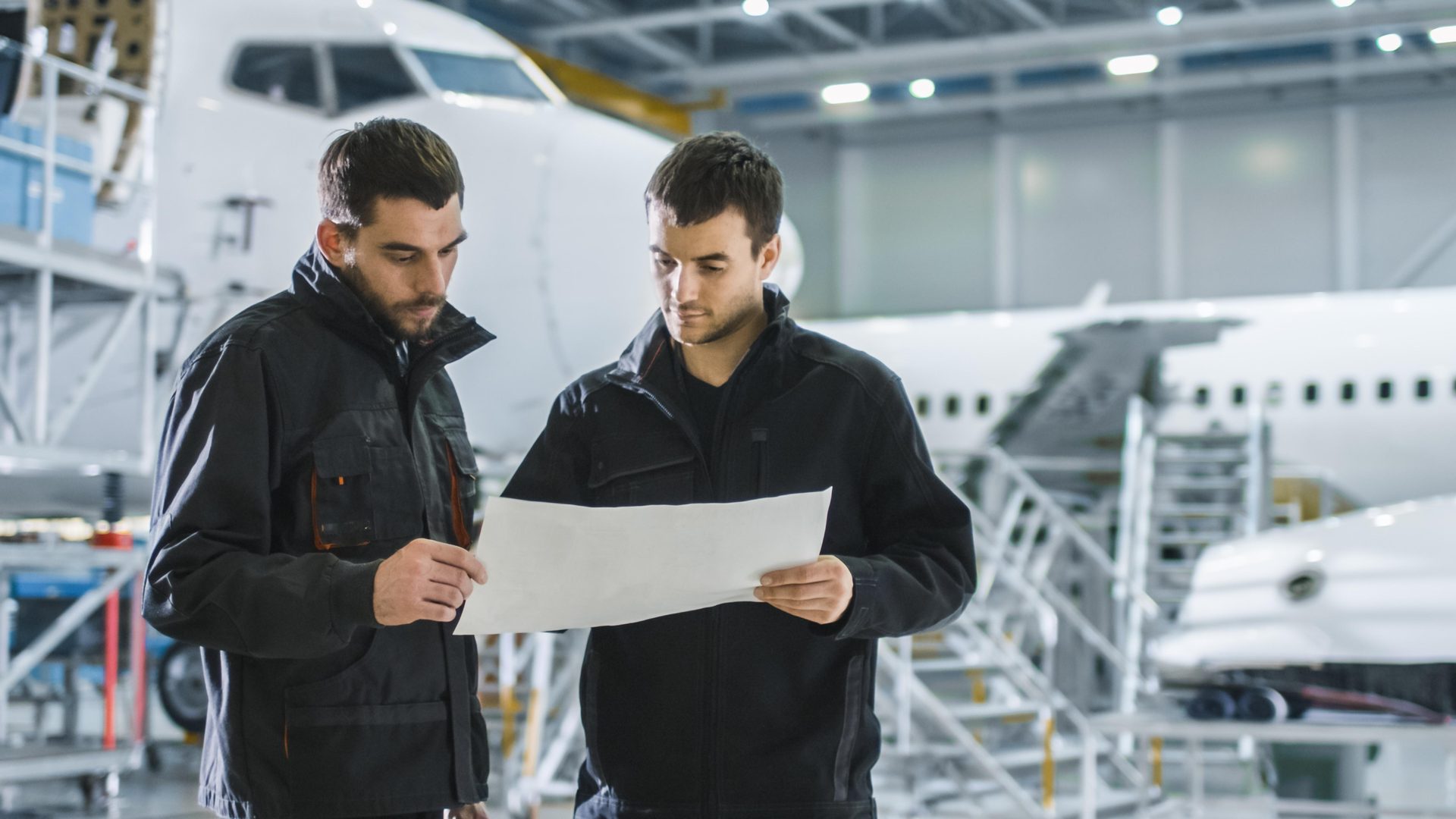 Engineers reviewing maintenance paperwork in front of an aircraft